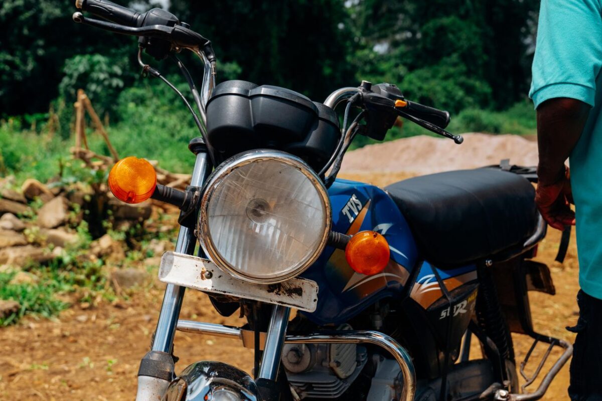 Close-up of a vintage motorcycle parked outdoors, showcasing headlight and handlebars in a sunny setting.