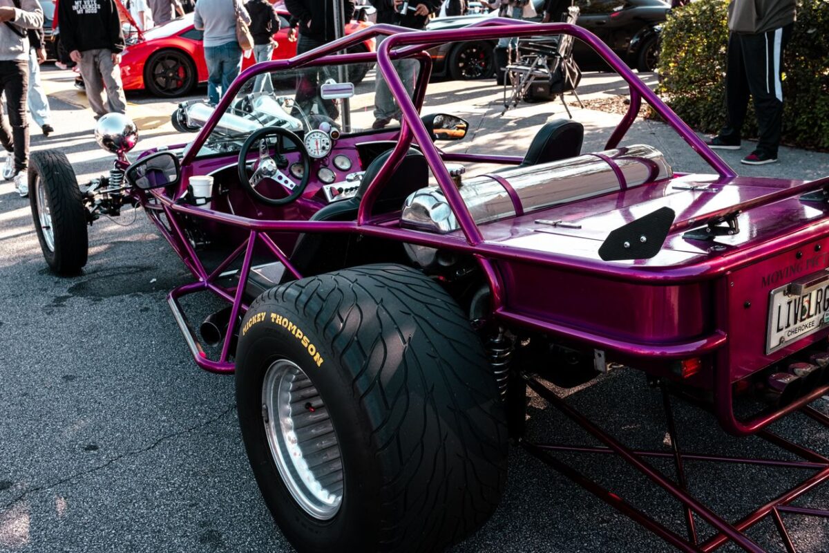 A striking custom trike displayed outdoors, showcasing unique design and vibrant colors at a car show.