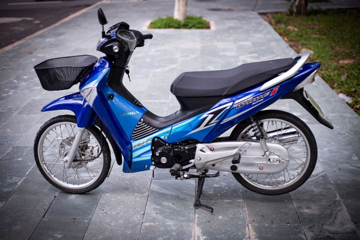 A blue motorcycle with sleek design parked on an urban sidewalk, offering a modern transportation solution.